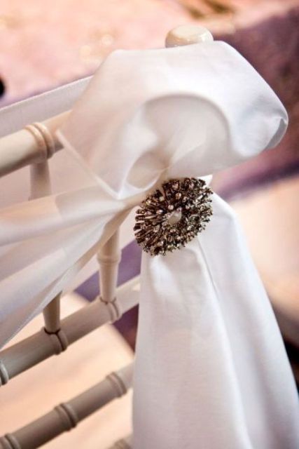 a white ribbon to accent a wedding chair and a large vintage brooch for a more chic and elegant look