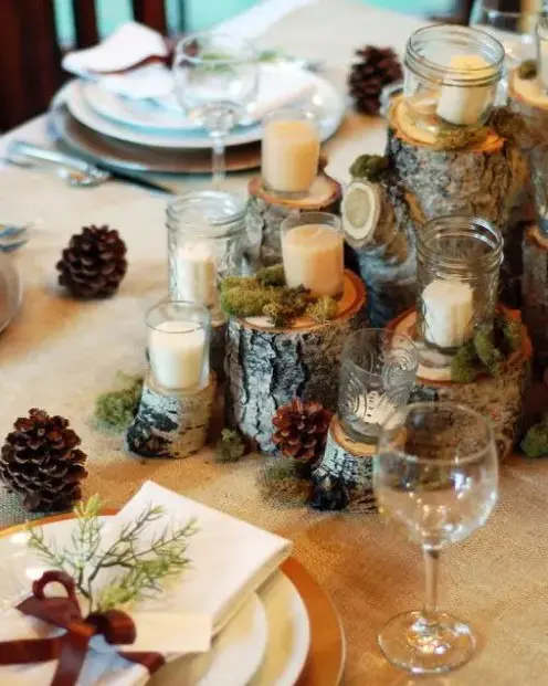 a woodland wedding centerpiece of tree stumps, moss, candles in jars and pinecones for a woodland or rustic wedding table setting