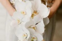 an elegant and refined white orchid wedding bouquet with a slight cascade for a refined bride, suitable for a tropical wedding