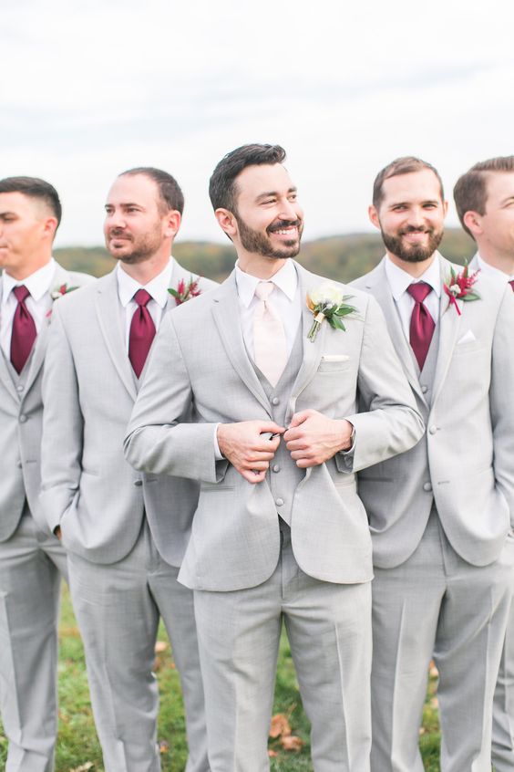 dove grey three piece suits, burgundy ties and bright boutonnieres for a chic and bold groomsmen's look