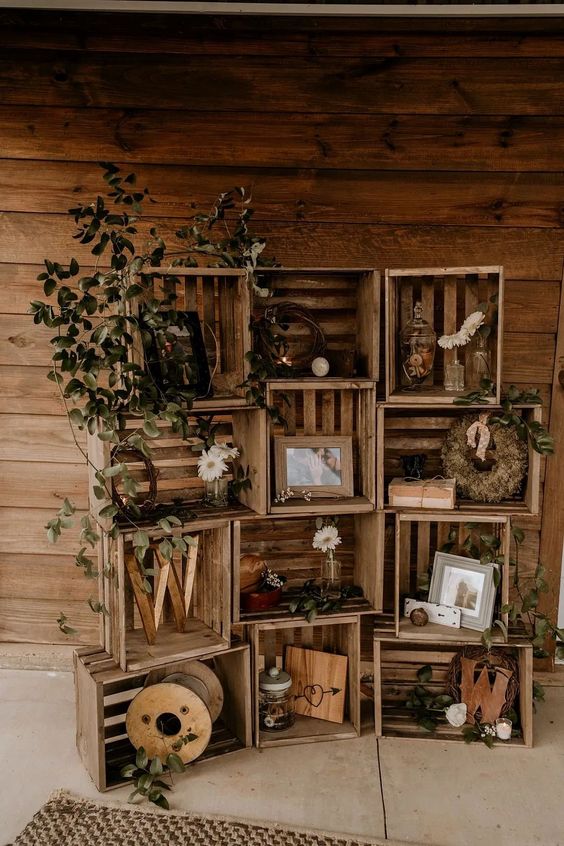 simple and cool rustic wedding decor of wooden crates with greenery and white blooms, monograms and photos plus signs