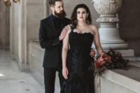 the couple wearing black, the groom in a black suit, shirt and tie, the bride in a black lace strapless wedding dress with a train