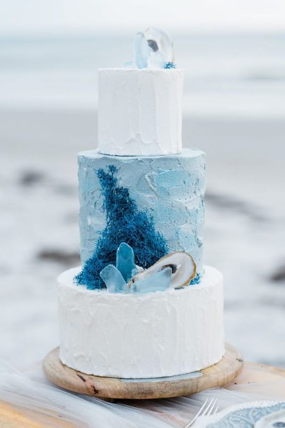 a beach-inspired wedding cake with blue and white textural tiers, with sugar corals, seaglass and seashells is amazing