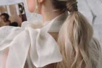 a beautiful and chic low ponytail with a braided touch, a bump on top and some waves down plus locks framing the face