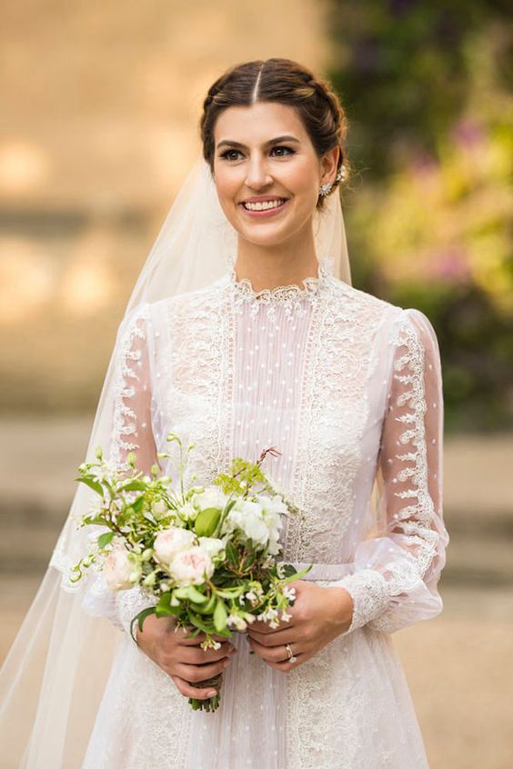 a beautiful and refined lace A-line wedding dress with a high neckline and detailed sleeves, statement earrings and a veil