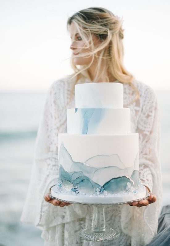 a beautiful coastal wedding cake in white, with blue waves, crystals looks very stylish and chic