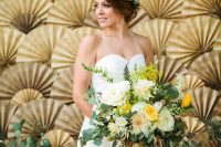 a beautiful gold paper fan and greenery wedding backdrop is a bold and cool idea to make a statement, it looks very fashionable and unusual