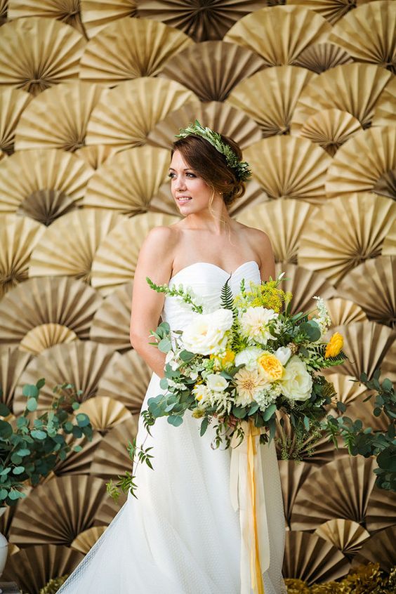 a beautiful gold paper fan and greenery wedding backdrop is a bold and cool idea to make a statement, it looks very fashionable and unusual