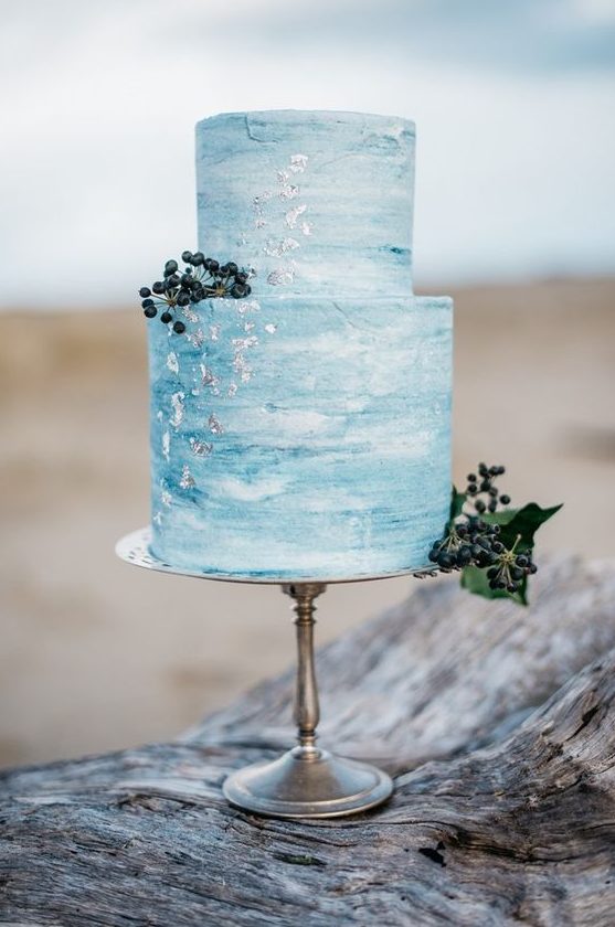 a blue watercolor wedding cake with silver leaf and privet berries is a nice idea for a beach wedding
