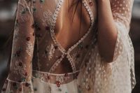 a boho wedding dress with a semi sheer bodice with lace appliques and colorful floral embroidery that add romance
