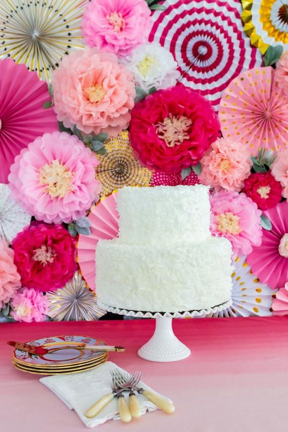 a bright wedding backdrop with pink and blush paper blooms, with pink and red striped paper fans is amazing