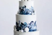 a catchy navy, blue and white wedding cake with brushstrokes and white macarons and meringues for decor