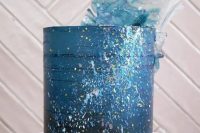 a chic and cool blue wedding cake with metallic touches, bright splatters and blue and clear sugar waves on top is great for an ocean wedding