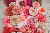 a colorful paper fan wedding backdrop with pink, orange, grey and red paper fans is a lovely idea for a wedding