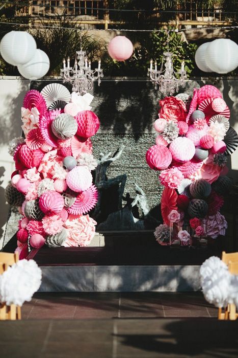 a colorful wedding altar with pink and grey paper balls and paper fans is a lovely idea for a modern bright wedding