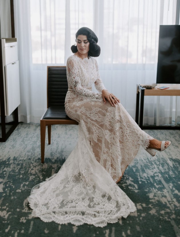 a creamy lace wedding dress with long sleeves, a high neckline, a trian and white block heels is ideal for a traditional wedding ceremony