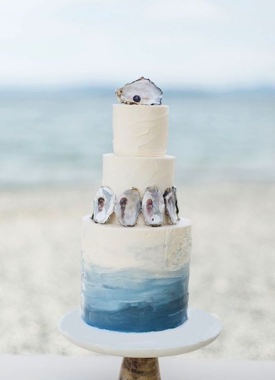 a creative ombre beach wedding cake with seashells and a black pearl is a lovely and chic idea to try