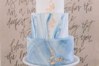 a delicate and subtle wedding cake with white and blue marble tiers, gold leaf is a trendy idea for a modern wedding done with blues