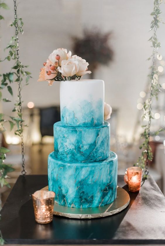 a fabulous turquoise watercolor wedding cake with gold touches, neutral and blush blooms on top and berries is a lovely idea for a summer wedding