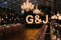 a gorgeous greenhouse wedding venue with chandeliers, bulbs over the table and oversized marquee letters