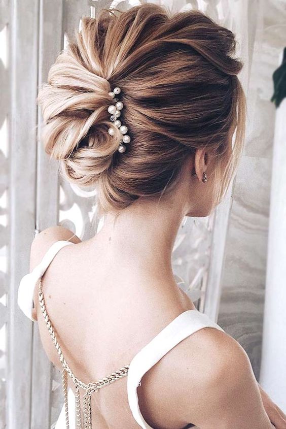 a gorgeous twisted wedding updo secured with a pearl hairpiece and with volume on top is a lovely idea for a refined wedding