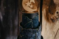 a jaw-dropping navy and midnight blue celestial wedding cake with a raw edge and gold touches plus a moon holding the upper tier