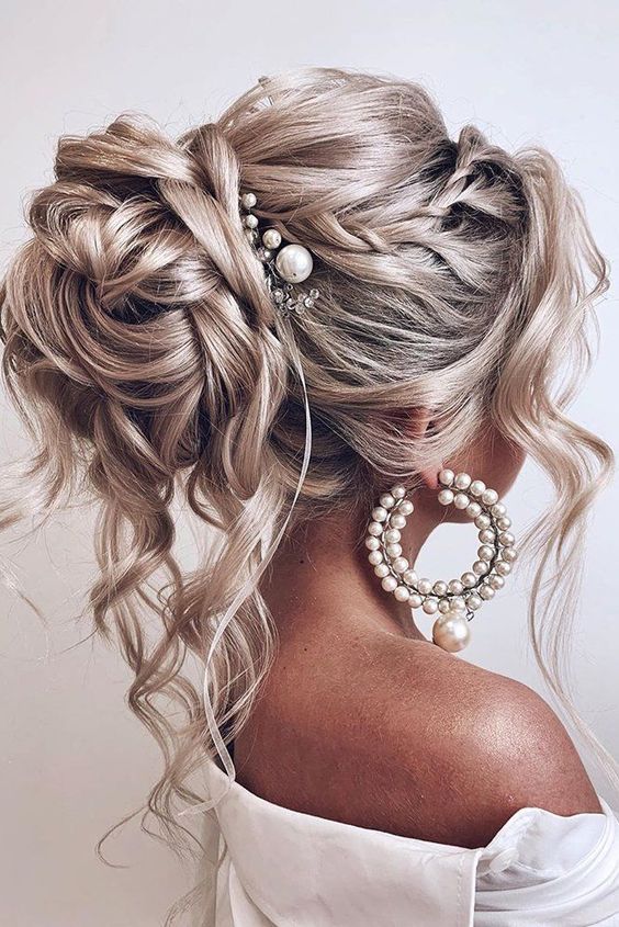 a jaw-dropping wedding hairstyle for long hair, a volume on top, a braided halo, a top knot with waves and curls accented with a pearl hairpiece