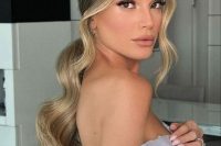 a low wavy ponytail with locks framing the face and central parting is a classic hairstyle for a modern and refined bride