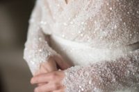 a modern glam wedding dress with pearls and sequins on the bodice and long sleeves contrast the plain skirt