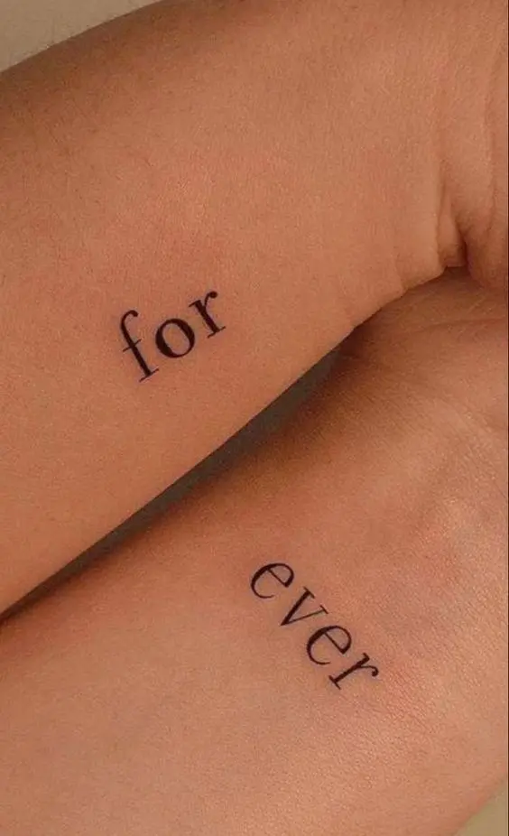 a modern idea of a wedding or couple tattoo with 'forever' split into two and placed on two wrists