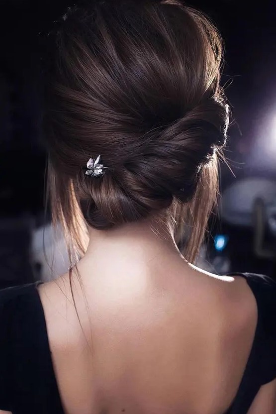 a modern low updo with a twisted low chignon and a voluminous top plus some locks down is a stylish idea