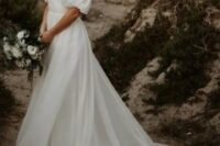 a modern wedding ballgown with a draped bodice and a square neckline, puff sleeves, a long veil and a long train for a romantic look