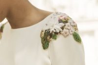 a modern white wedding dress with a high neckline and colorful embroidered flowers and leaves that accent it a lot