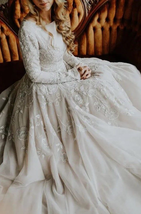 a modest but jaw-dropping A-line wedding dress with long sleeves, lace appliques, a bateau neckline