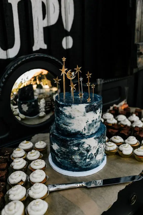 a navy and white watercolor wedding cake with gold star toppers is a very chic and bold solution for a modern wedding with a celestial theme