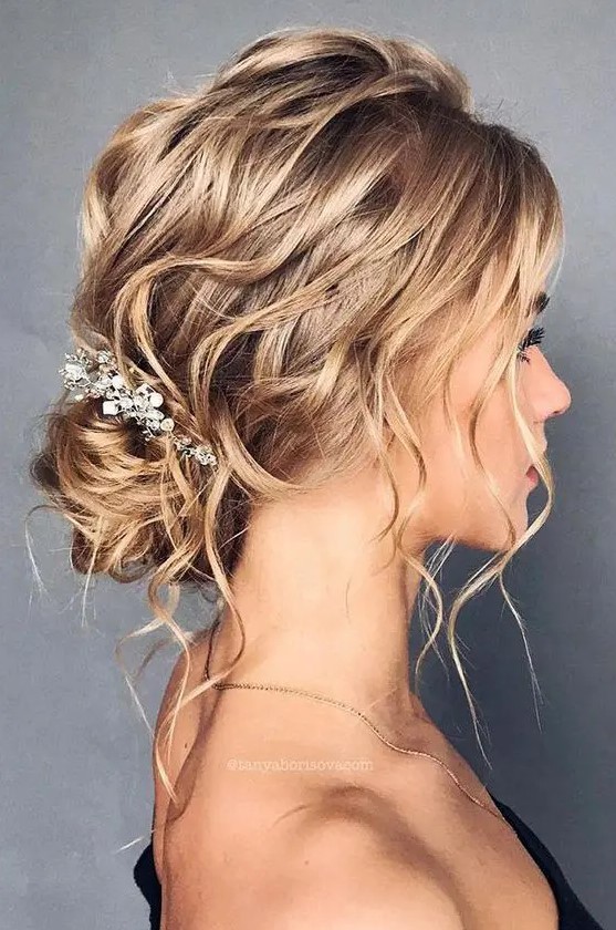 a refined and wavy messy low bun with a wavy top, locks down and an embellished hairpiece is a chic idea