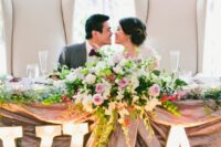 a refined wedding sweetheart table decorated with blooms, greenery and large marquee monograms is amazing