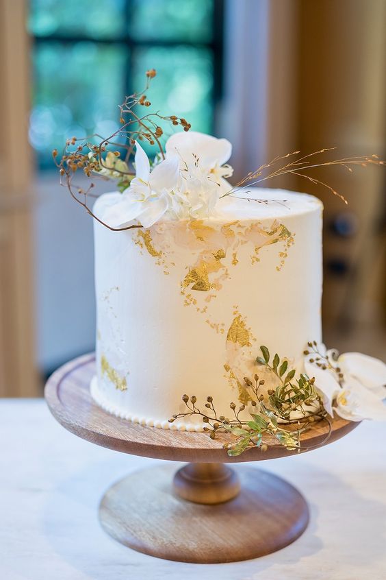 a refined white wedding cake with gold leaf, white orchids and gilded touches is a stunning idea to rock