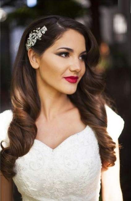 a romantic long curly hairstyle with an S-lock to frame the face and a refined embellished hairpiece