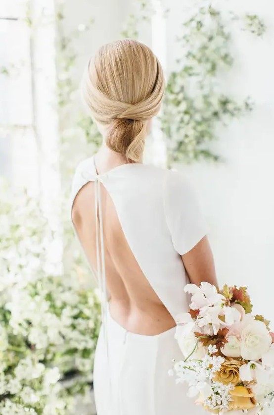 a sleek minimalist twisted low updo with a sleek top is ideal for a minimalist bride