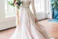 a sophisticated blush wedding dress with white lace, an illusion neckline, long sleeves and a long train