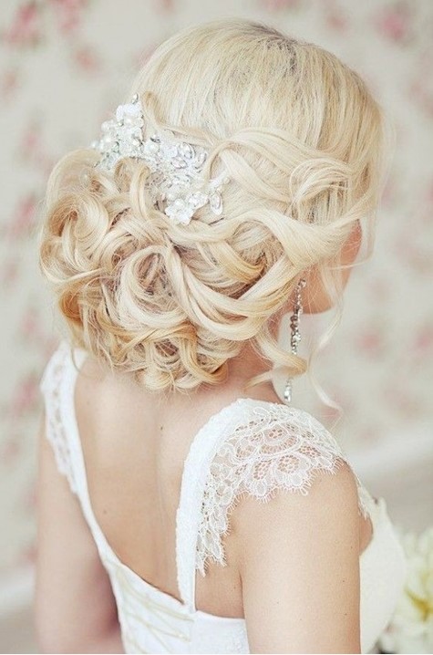 a stunning low wedding updo on long hair with a shiny rhinestone hairpiece and a slight volume on top