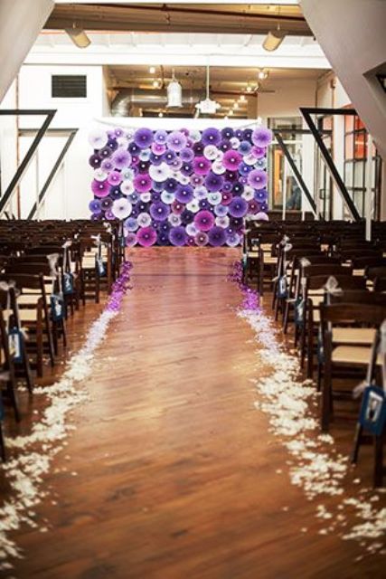 a super bold purple, fuchsia and white paper fan wedding backdrop, matching purple petals on the floor is cool