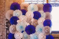 a super colorful wedding backdrop of white, blue, blush and bold purple paper fans is a very budget-friendly and cool solution to rock