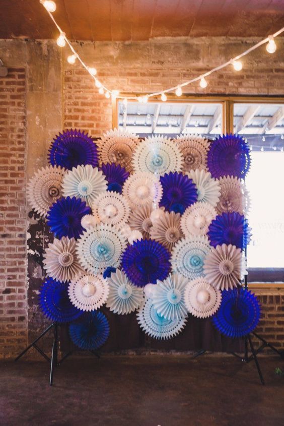 a super colorful wedding backdrop of white, blue, blush and bold purple paper fans is a very budget-friendly and cool solution to rock