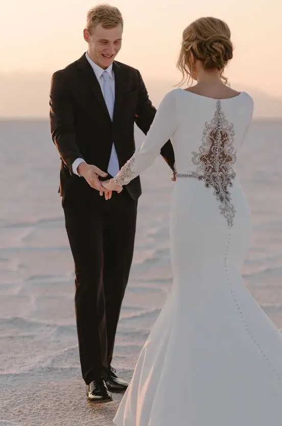 a unique plain white mermaid wedding dress with a unique lace and rhinestone detail on the back and matching sleeves is wow