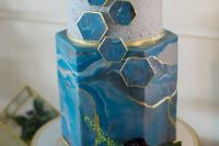 a vibrant blue wedding cake with a marble effect, a concrete tier, blue marble hexagons and gold touches is very chic and beautiful