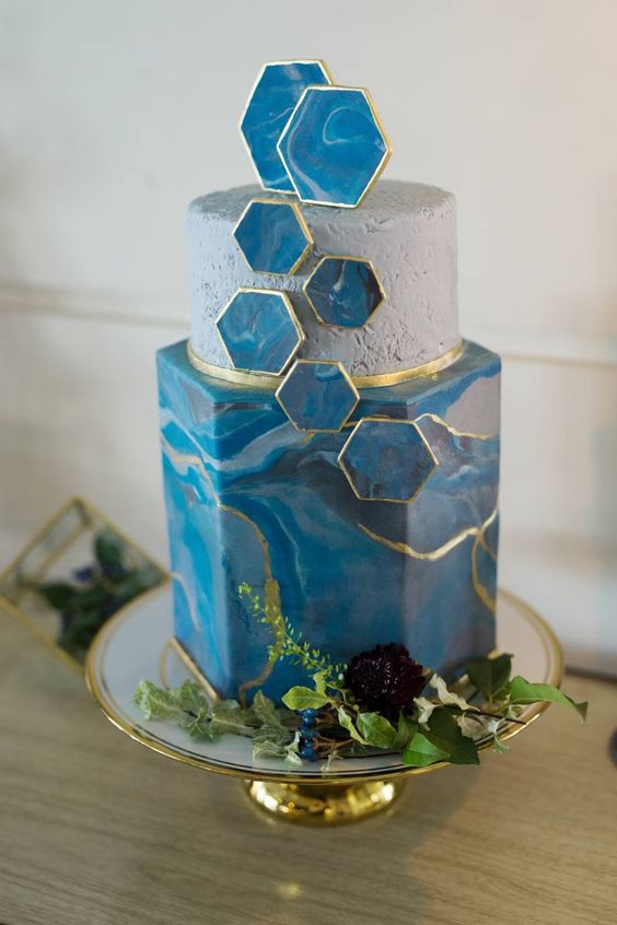 a vibrant blue wedding cake with a marble effect, a concrete tier, blue marble hexagons and gold touches is very chic and beautiful