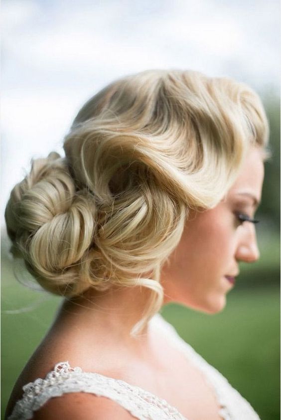 a vintage wavy low updo with a large bun and some locks down for ultimate elegance
