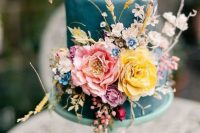 a whimsy blue wedding cake with pink, yellow, lilac, blue blooms, wheat and some neutral blooms, too is amazing